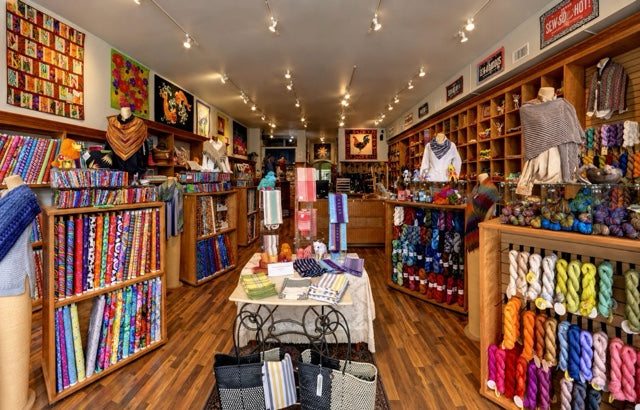 The Quilted Skein store interior: shelves of fabric bolts and yarn